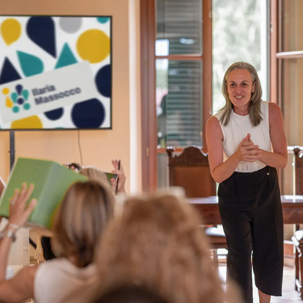 Ilaria Massocco in aula davanti a un gruppo di partecipanti, alcuni con la mano alzata