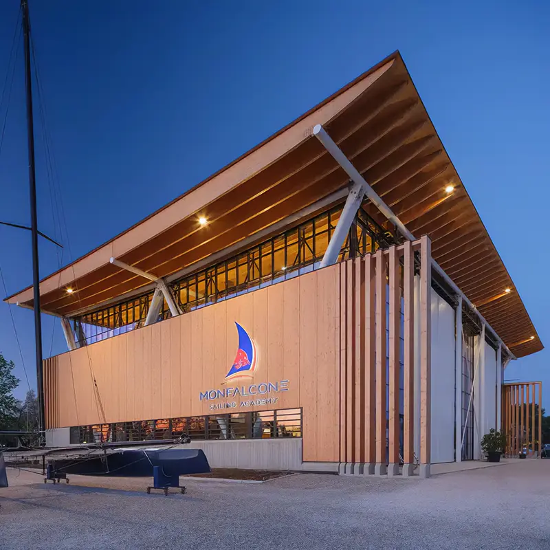 L'hangar della Monfalcone Sailing Academy visto da fuori: edificio rivestito in legno con un grande tetto sporgente